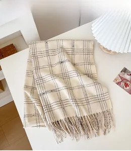 Detail of soft cream plaid scarf with fringe tassels and subtle metallic gold threads