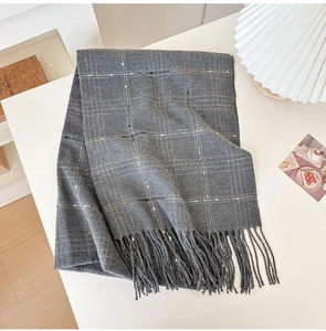 Detailed view of grey plaid cashmere scarf featuring soft fringe edges and golden stripes
