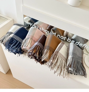 Macro shot of assorted classic British plaid scarves with high-quality tassel edge details