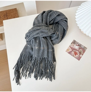 Detail of gray plaid scarf with elegant fringe and golden striped weave texture