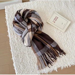 Close-up of classic British plaid scarf texture with soft tassels on a white rug