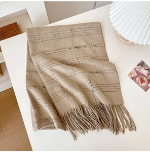 Detailed flat lay of a cashmere-like plaid scarf with golden stripes and fringe edges