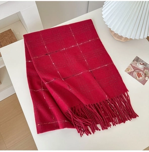 Detail of red plaid cashmere scarf featuring elegant tassel fringe and soft knit texture