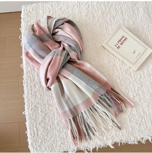 Close-up of pink and grey plaid scarf featuring soft tassels and woven texture details