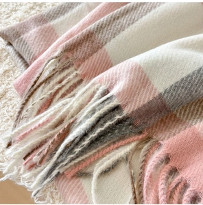 Detailed view of pink and brown plaid scarf with soft tassels and woven texture