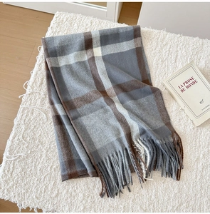 Macro view of plaid winter scarf with thick fringes on soft faux fur surface