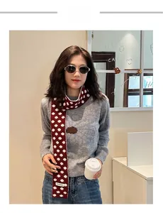 Detail of red and white polka dot knitted scarf paired with a casual sweater