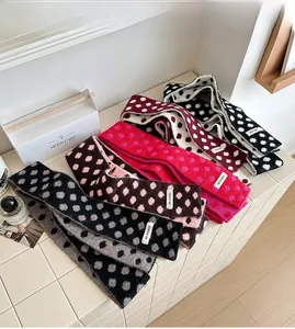 Detail of five polka dot knitted scarves in various colors with KN STUDIO woven labels