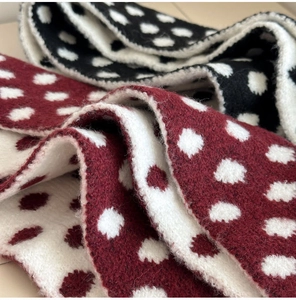 Detail of soft knit scarf featuring double-sided polka dot pattern in red and black