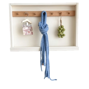 Light blue minimalist knit wool scarf hanging on a wooden hook for winter style