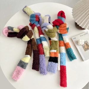Detailed shot of four colorful striped knitted scarves with branded woven labels on a white table