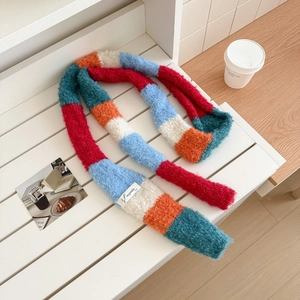 Detail of soft mohair rainbow striped scarf with vegetable label on a white bench