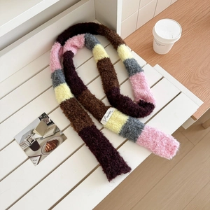 Detail of colorful rainbow knit scarf with 'vegetable' tag on a white wooden bench