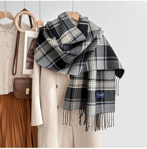 Détail d'une écharpe classique à carreaux noir et blanc avec de longues franges sur manteau