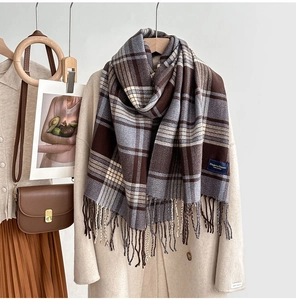 Détail d'une écharpe à carreaux avec franges stylisée sur un manteau en laine beige