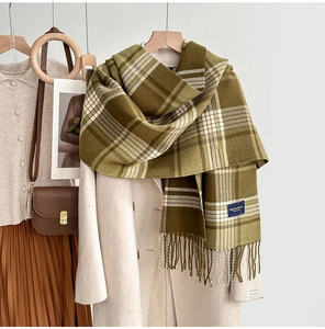 Détail d'une écharpe à carreaux avec franges sur un manteau beige et sac vintage