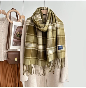 Détail d'une écharpe à carreaux vert olive et beige avec franges et étiquette tissée