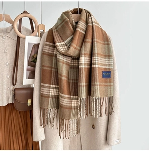 Détail de l'écharpe à carreaux avec franges et étiquette classique sur manteau blanc