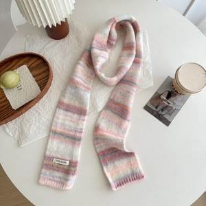 Détail d'une écharpe en maille mélange de laine aux rayures pastel sur table blanche