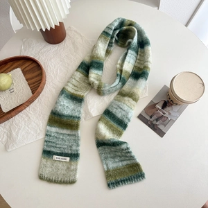 Détail d'une écharpe en tricot à rayures vertes dégradées avec étiquette laine