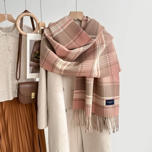 Écharpe à carreaux rose et marron avec franges portée sur un manteau beige