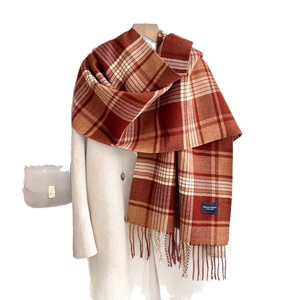 Écharpe à carreaux et franges rouge et orange sur un manteau blanc avec sac bandoulière