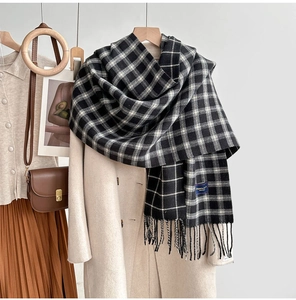 Detail of plaid tassel scarf styled with beige coat for an elegant winter look