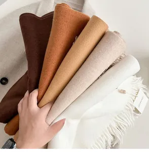 Close-up of stacked cashmere-feel scarves with soft fringe details in earthy tones