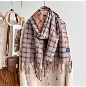 Detail of soft checkered scarf with orange and grey-blue patterns and fringe trim