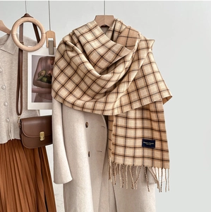 Close-up of soft plaid scarf with fringe tassels and Elegance Classic woven label
