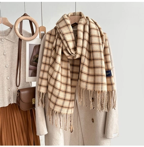 Detail of beige plaid scarf with tassels styled on a wool coat for autumn