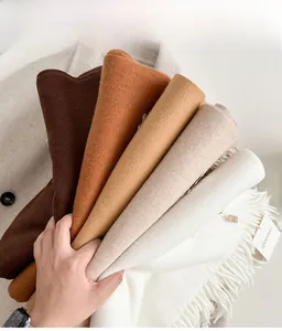 Close-up of five neutral-toned cashmere scarves with delicate fringe details