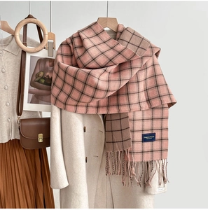 Detail of pink and brown plaid cashmere scarf with soft fringes and elegant brand label