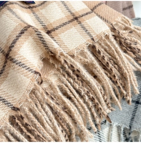Close-up of soft plaid scarf fabric with tassel fringe in cream and coffee tones