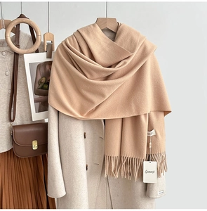 Detail of light camel cashmere-feel scarf with elegant fringes over a wool coat