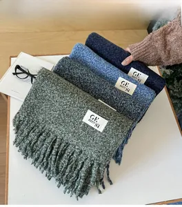 Detail shot of multi-color thick knit scarves with fringe and brand label on white desk
