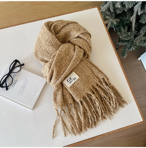 Close-up of thick camel wool scarf texture with soft tassels and woven brand label