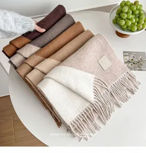 Close-up of double-sided wool scarf fringe detail with gradient earth tones and label