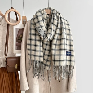 Classic plaid tassel scarf in beige and charcoal grey styled on a wool coat
