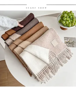 Close-up of double-sided wool scarves with fringe detail and luxury leather labels