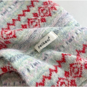 Close-up of Fair Isle knit scarf featuring soft long plush texture and red geometric patterns