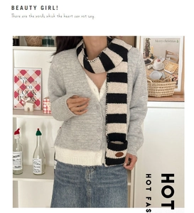 Detail shot of a soft wool blend black and white striped scarf with a small oval tag