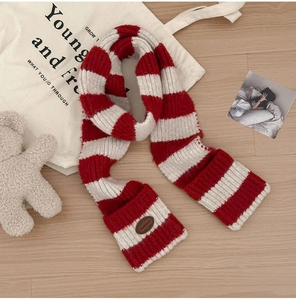 Detail of red and white striped wool blend scarf with decorative brown leather patch