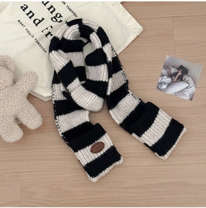 Close-up of black and white striped knit scarf with brown leather patch detail