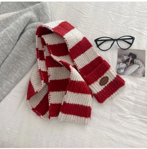 Macro detail of red and white striped knit wool scarf with brown leather logo patch
