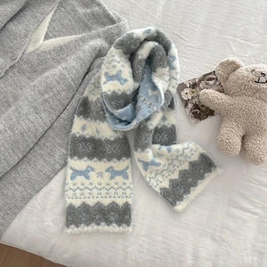 Detail shot of Fair Isle knit scarf with blue dog and snowflake patterns on white bedding