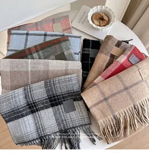 Detail of wool blend plaid scarf with tassel fringe and stitched leather logo label