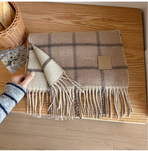 Detailed close-up of wool plaid scarf with leather tag and elegant fringe edges