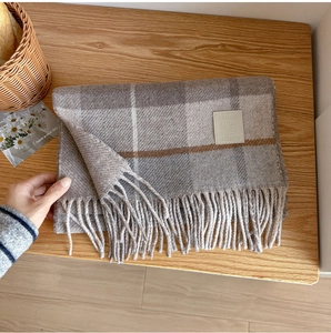 Close-up of wool plaid scarf texture with elegant fringes and a premium leather tag