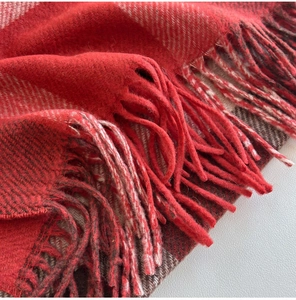 Macro view of red and brown plaid wool scarf texture with detailed fringe tassels